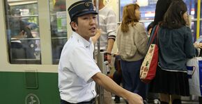 Hiroshima. Bij een drukke tramhalte maant een ‘opzwaaier’ reizigers snel in te stappen. 