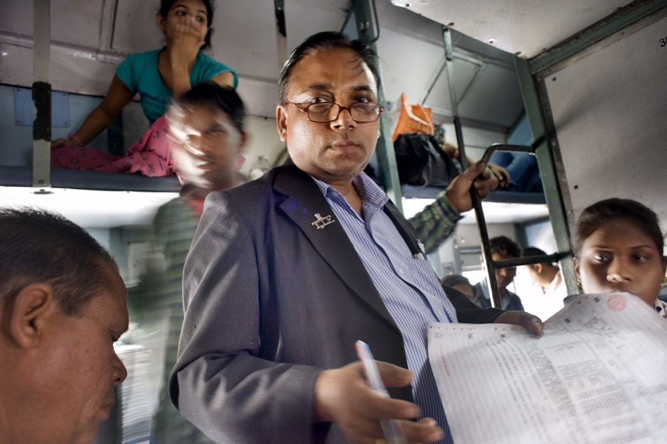 Conducteur controleert de passagierslijst in de trein van Bhopal naar Indore.